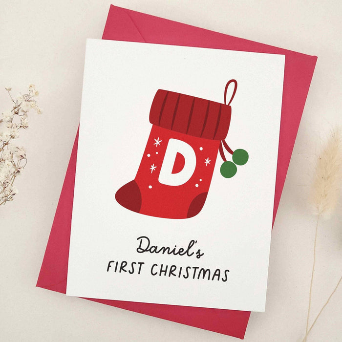 Festive First Christmas stocking card with name personalization, shown with red envelope – XOXOKristen