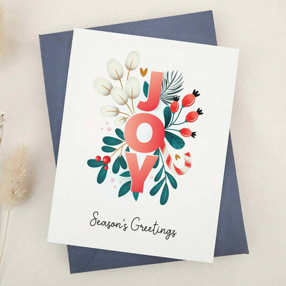 Standing card with “JOY” floral design and “Season’s Greetings” text, displayed with a coordinating envelope — XOXOKristen.